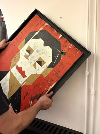 Ein stilisiertes Portrait von Helene Weigel wird aufgehängt.