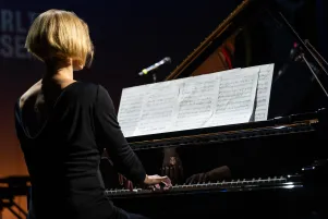 Joana Mallwitz am Klavier sitzend, von hinten fotografiert