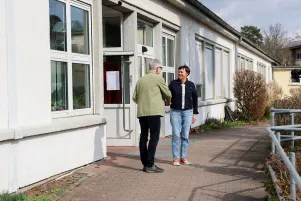 Oliver Reese und Birgit Deininger begrüßen sich vor dem Schulgebäude