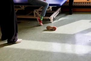 Auf dem Boden liegt ein einzelner ausgezogener Schuh vor der Behandlungsliege. 