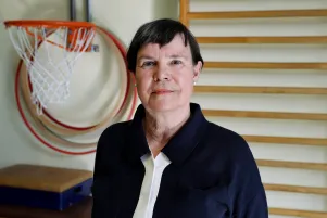 Ein Portrait von Birgit Deininger, hinter ihr Basketballkorb und Sprossenwand. 