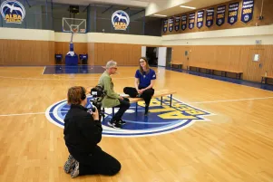 Behind the scenes bild aus der Alba-Trainingshalle, im Vordergrund ist der Kameramann zu sehen, in der Mitte des Bildes unterhalten sich Oliver Reese und Wiebke Schwartau