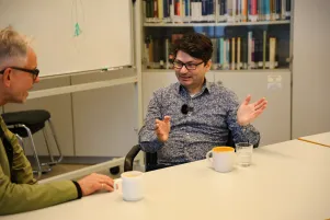 Taylan Akdag im Gespräch, er gestikuliert und schaut zu Oliver Reese im linken BIldrand.