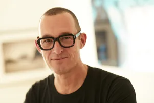 Albert Ostermaier mit Brille und schwarzem T-Shirt, der Hintergrund ist unscharf.