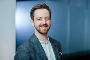 Mattia Nelles vor blauer Wand, schaut in die Kamera.