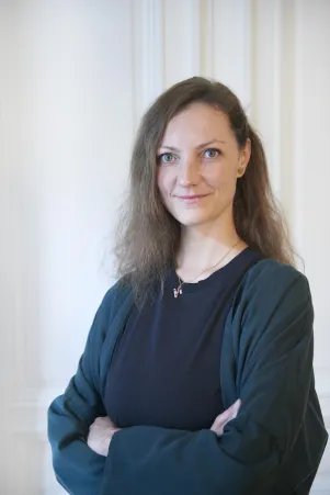 Nadya Hartmann mit verschrenkten Armen vor weißer Wand.