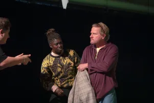 Joyce Sanhá und Peter Moltzen in Probenkostümen sind einander zugewandt, am linken Bildrand ist noch eine weitere gestikulierende Person zu entdecken. 