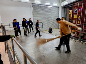 Bühnentechniker bereiten mit einem Reisigbesen die Ladefläche vor.