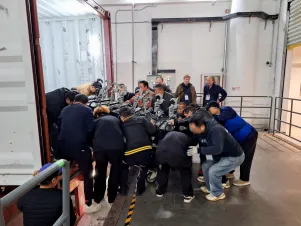 Eine große Gruppe an Technikern trägt ein schweres Bühnenteil aus dem LKW. 