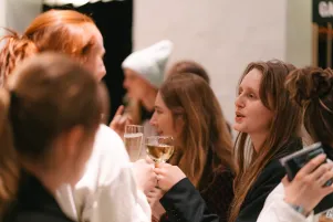 Schnappschuss vom Publikum, in der Menge ist Kathleen Morgeneyer zu erkennen, sie hält ein Glas Wein in der Hand und scheint sich zu unterhalten. 