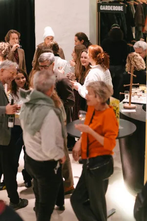 Schnappschuss im Foyer des Neuen Hauses. Das Bild ist etwas erhöht aufgenommen und zeigt Menschen, die sich unterhalten und Sekt trinken. 