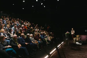 Blick von der Seitenbühne: Links ist der gefüllte Zuschauerraum zu erkennen, rechts die Bühne des Neuen Hauses. 
