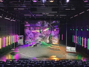 Das Bühnenbild von "es kann doch nur noch besser werden2 in der Frontalansicht. Die Lichter der Videowände spiegeln sich im Bühnenoden wider. 