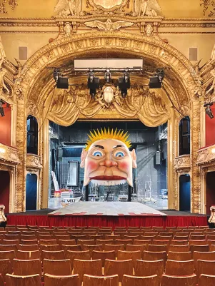 Auf der Bühne vor leeren Zuschauerraum ist ein riesiger Kopf zu erkennen. 