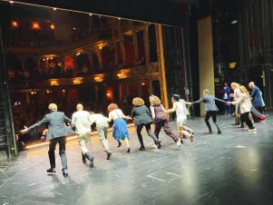 Schnappschuss vom Premierenapplaus von "K.": Das Produktionsteam rennt Hand in Hand von der Bühnenmitte zur Rampe, um sich dort zu verbeugen. 