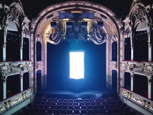 Das Große Haus ist dunkel, das Foto wurde aus dem zweiten Rang mit Blick auf die Bühne aufgenommen. Im vorderen Teil der Bühne leuchtet das Bühnenbild von "De Profundis" hell und scheint dadurch zu schweben.  