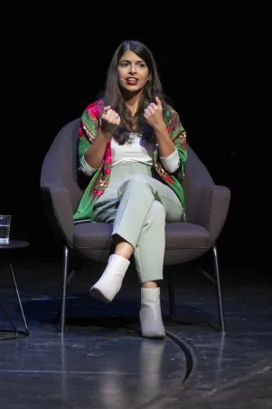 Schnappschuss von Daniela Sapehri, sie trägt als einzige ein buntes Outfit, das Foto ist frontal von ihr aufgenommen, sie gestikuliert mit beiden Händen. 