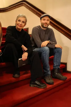 Marion Brasch und Marc-Uwe Kling sitzen auf der roten Samttreppe zum Aufgang in den ersten Rang des Großen Hauses. 