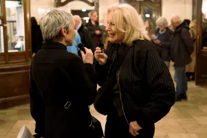 Maren Kroymann und Marion Brasch unterhalten sich im Foyer des Großen Hauses. Sie sind einander zugewandt, im Hintergrund ist Publikum zu erkennen. 
