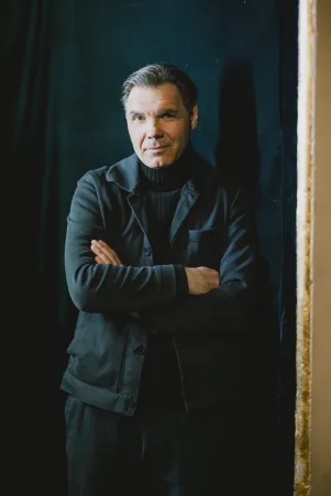 Max Hopp steht mit verschränkten Armen an eine Wand gelehnt.