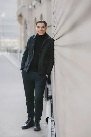 Max Hopp steht an eine Wand gelehnt, der Hintergrund ist unscharf.