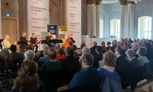 Schnappschuss vom Quartett aus der Publikumsperspektive. Es ist zu erkennen, dass der Saal gefüllt ist. 