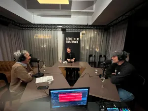 Schnappschuss während der Podcastaufnahme: Marion Brasch, Christiane Paul und Sebastian Zimmler sitzen Kopfhörer tragend an drei Tischen, die zu einem Dreieck aufgestellt sind.