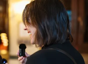 Schnappschuss von Christiane Paul im Profil. Sie hält das Mikrofon dicht vor ihren Mund und lacht. 