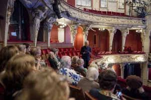 Mitglieder des Freundeskreises sitzen im ersten Rang des Großen Hauses, vor ihnen steht Oliver Reese und gestikuliert. 