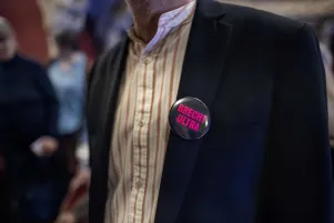 Nahaufnahme von einem Button auf dem "Brecht Ultra" steht und der an einem Jackett befestigt ist. 