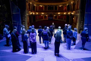 Die Mitglieder des Freundeskreises stehen auf der Bühne des Großen Hauses. Im Hintergrund ist der beleuchtete Zuschauerraum zu erkennen. 