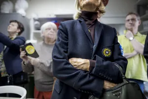 Schnappschuss: Es sind die Oberkörper verschiedener Menschen zu erkennen, an deren Oberteilen verschiedene Buttons und Sticker des Freundeskreises heften. 