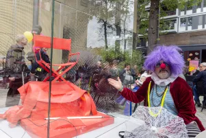 Schnappschuss von der Weigelskulptur. Eine Person ist als Clown verkleidet und zeigt auf die Skulptur .