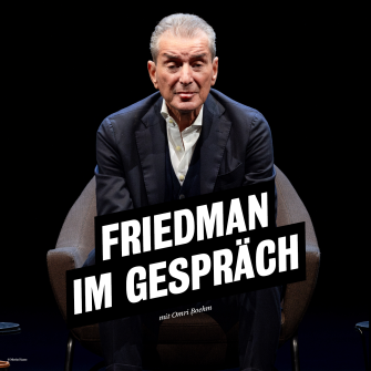 Ein Portrait von Michel Friedman, er sitzt in dunklem Anzug vor dunklem Hintergrund und schaut direkt in die Kamera. 