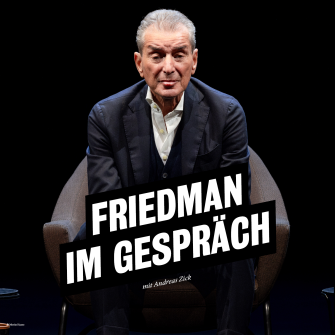Michel Friedman sitzt auf einem dunklen Sessel vor dunklem Hintergrund. Er trägt einen dunklen Anzug über einem weißen Hemd und schaut, die Arme auf die Knie lehnend, direkt in die Kamera. 