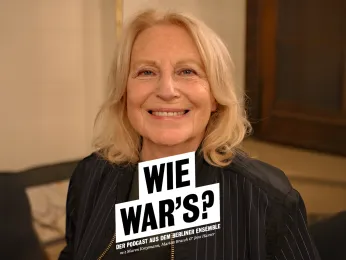 Portrait von Maren Kroymann im Foyer des Großen Hauses. Sie lacht breit und schaut direkt in die Kamera. 