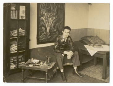 Bertolt Brecht in einem privaten Umfeld auf dem Bett sitzend