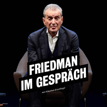 Michel Friedman sitzt auf einem Lehnstuhl, der Hintergrund ist dunkel, er trägt einen dunklen Anzug mit weißem Hemd. Er lehnt sich vor und schaut frontal in die Kamera. 