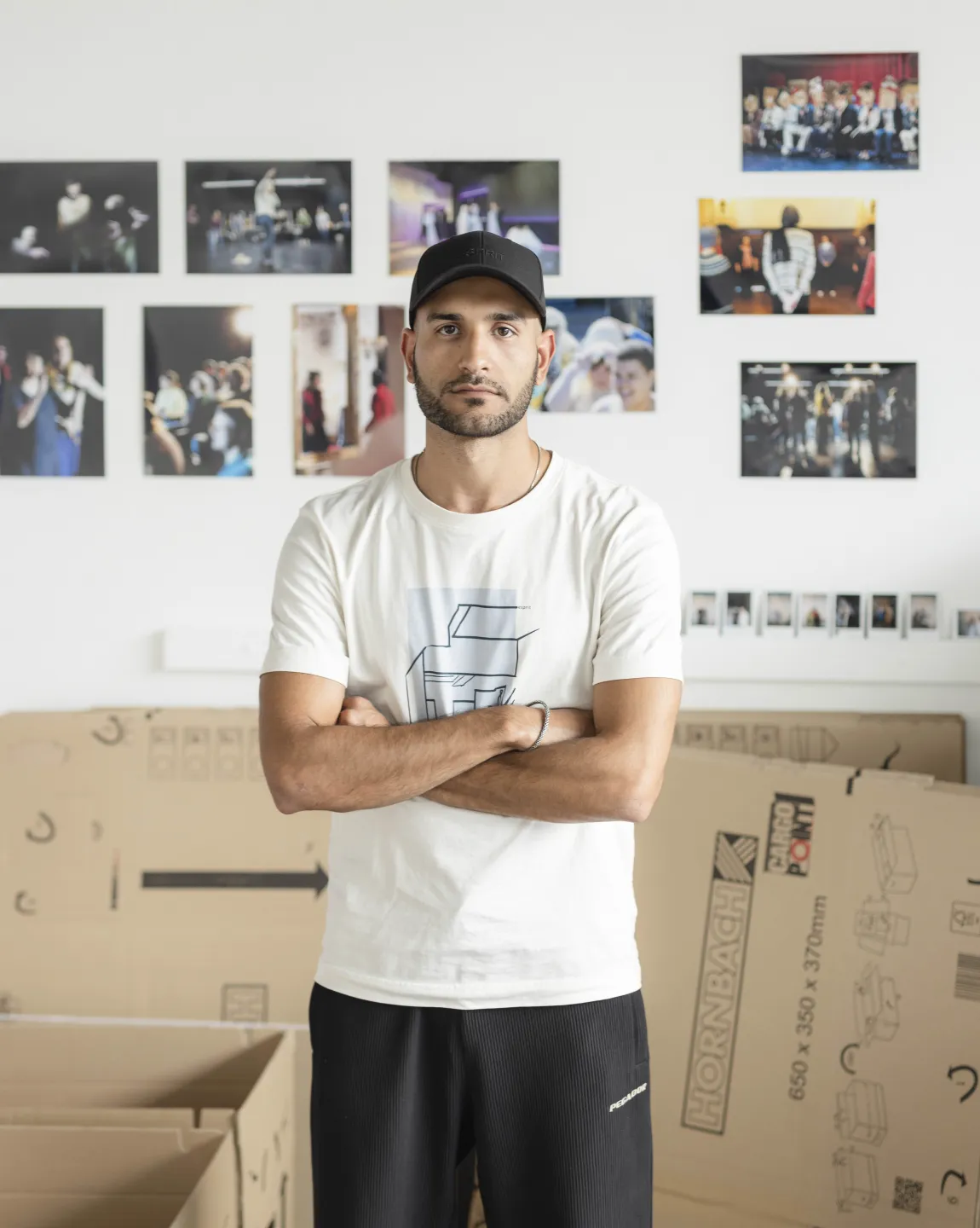 Alireza Daryanavard im Gartenhaus des Berliner Ensembles, hinter ihm Bilder an einer Wand und ein Umzugskarton