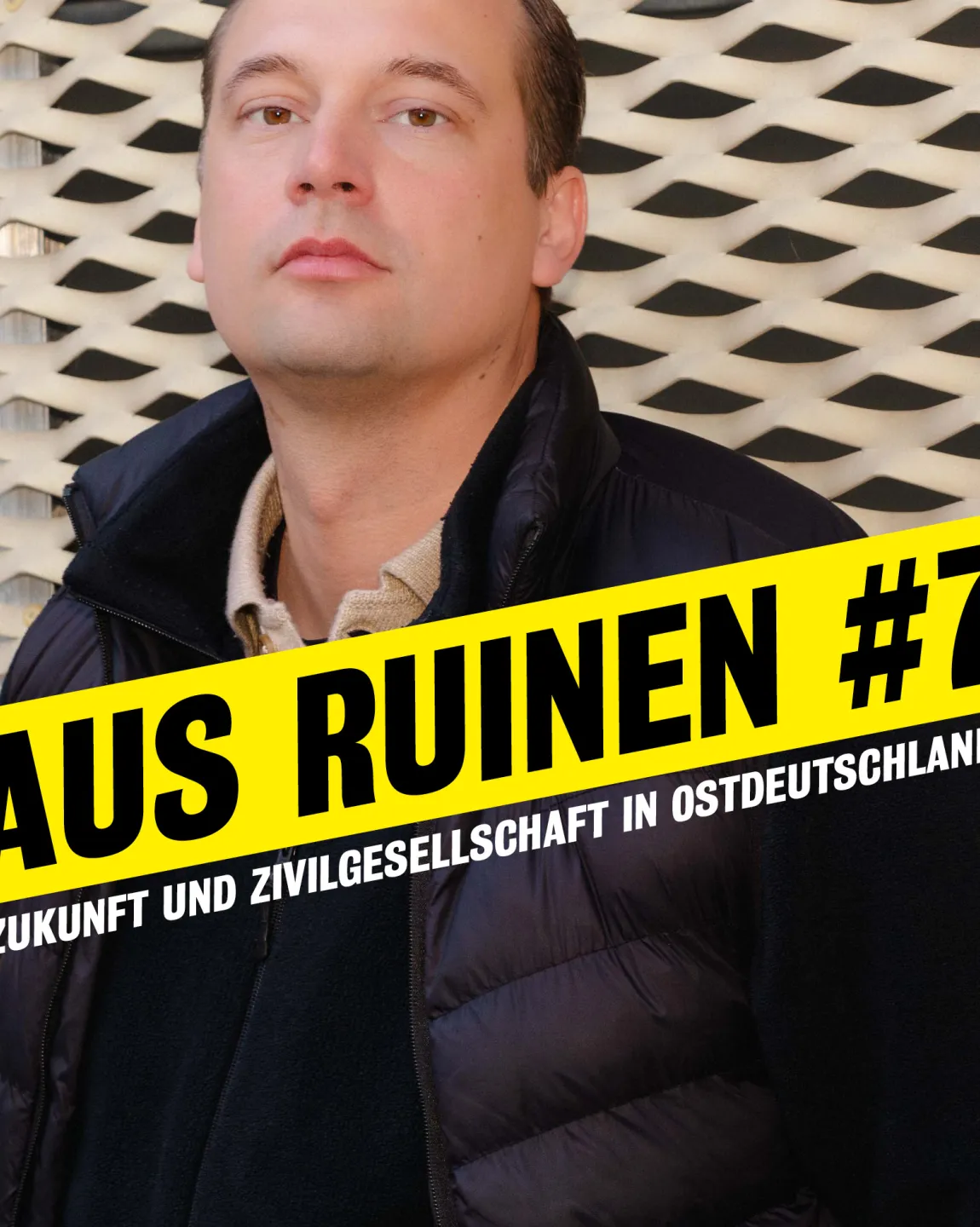 Portrait von Hendrik Bolz im Halbprofil vor dem neuen Haus. Darauf steht "Aus Ruinen #7. Zukunft und Zivilgesellschaft in Ostdeutschland."
