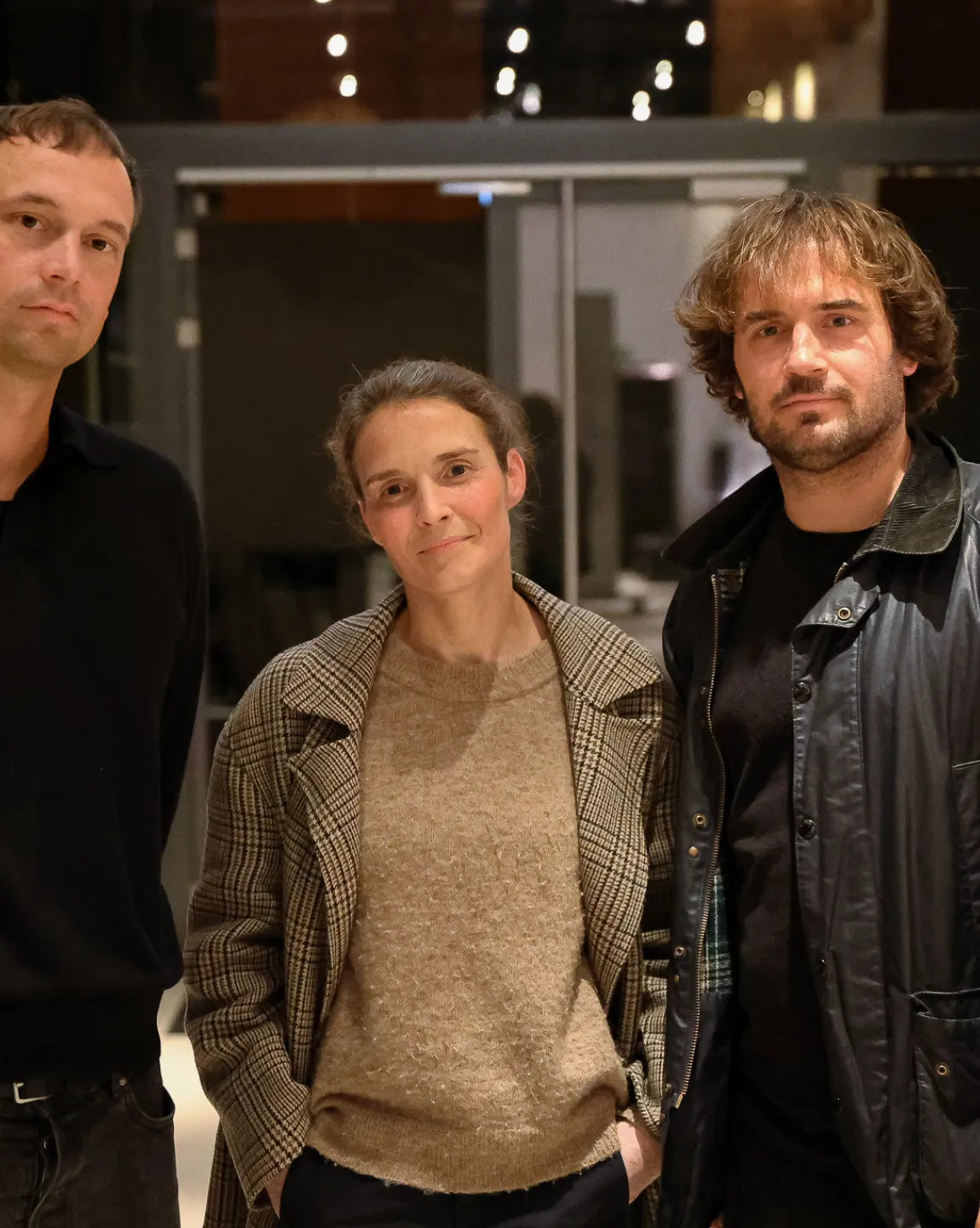 von links nach rechts: Hendrik Bolz, Caterina Lobenstein, Johannes Nölting. Die drei stehen dicht beieinander im Foyer des Neuen Hauses und schauen direkt in die Kamera.