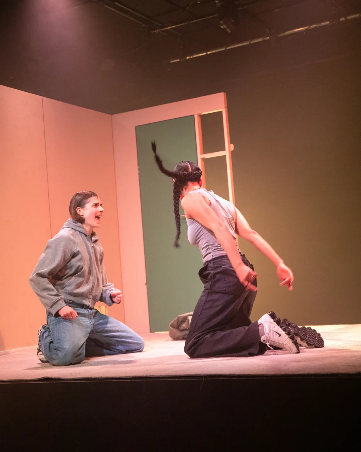 Amal Keller und Amelie Willberg auf dem Boden eines Wohnzimmers (Bühnenbild). Sie bewegen sich, Amal ist mit dem Rücken zum Publikum.