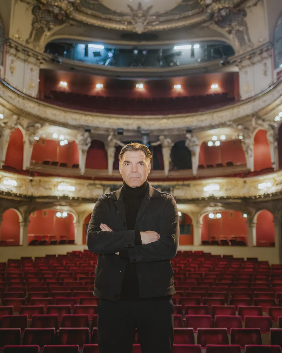 Max Hopp auf der Bühne im Großen Haus des Berliner Ensemble. Im Hintergrund der prunkvoll verzierte Zuschauersaal.
