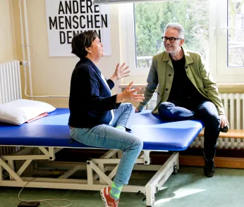 Birgit Deininger und Oliver Reese sind lebhaft im Gespräch. Im Hintergrund steht auf einem Plakat: "Andere Menschen denken."