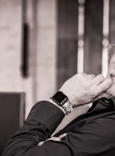 Schwarz-weiss-Aufnahme von Eric Dunlap im Halbprofil mit Brille. Im Hintergrund ist ein Laptop zu erkennen, seine linke Hand hält er an sein Kinn, er trägt Ehering und AppleWatch.