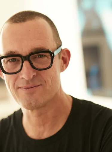 Albert Ostermaier mit Brille und schwarzem T-Shirt, der Hintergrund ist unscharf.