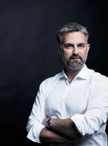 Anders Levermann in weißem Hemd steht mit verschrenkten Armen vor einem Schwarzen Hintergrund, schaut in die Kamera.