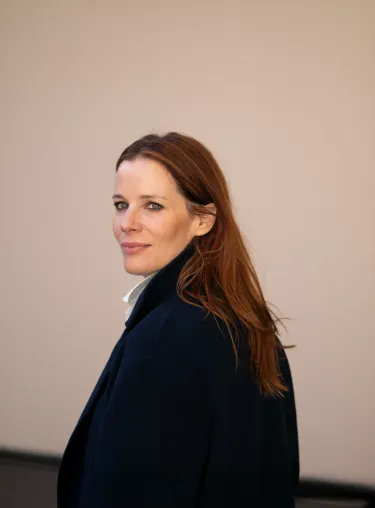 Florence Gaub in dunklem Oberteil blickt über die Schulter in die Kamera.