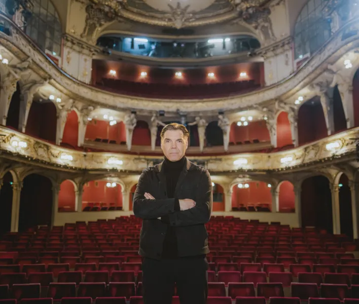 Max Hopp auf der Bühne im Großen Haus des Berliner Ensemble. Im Hintergrund der prunkvoll verzierte Zuschauersaal.
